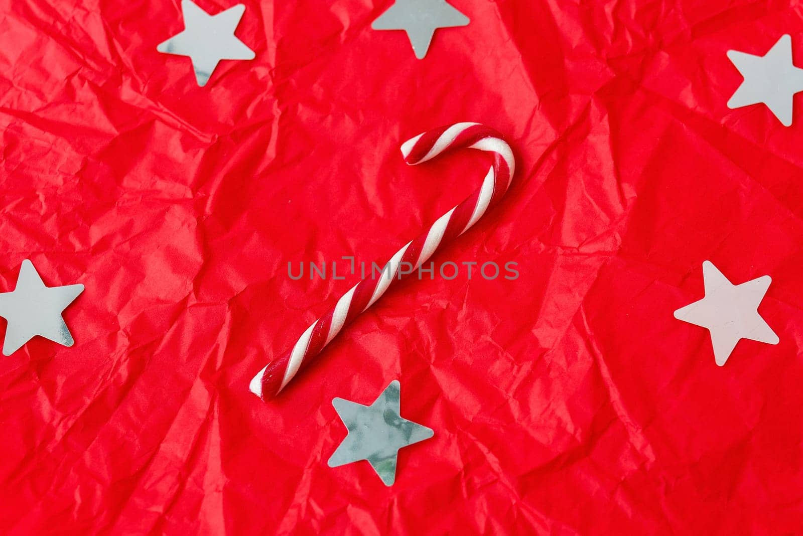 This is a bright and colorful Christmas background with white stars, a candy cane, and a crumpled texture. by sfinks