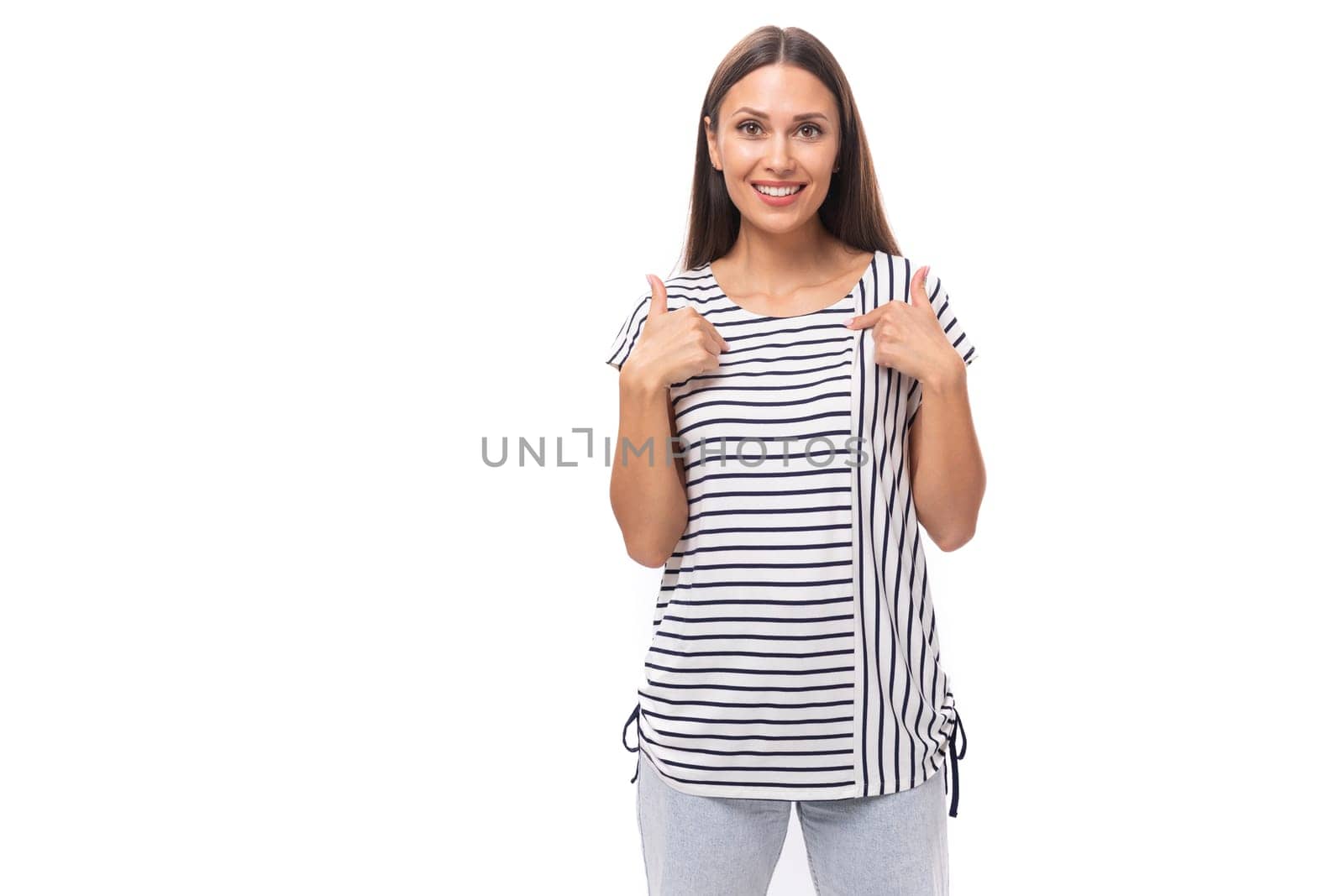 young beautiful brunette lady with straight hair is dressed in a striped t-shirt and jeans on a white background with copy space by TRMK