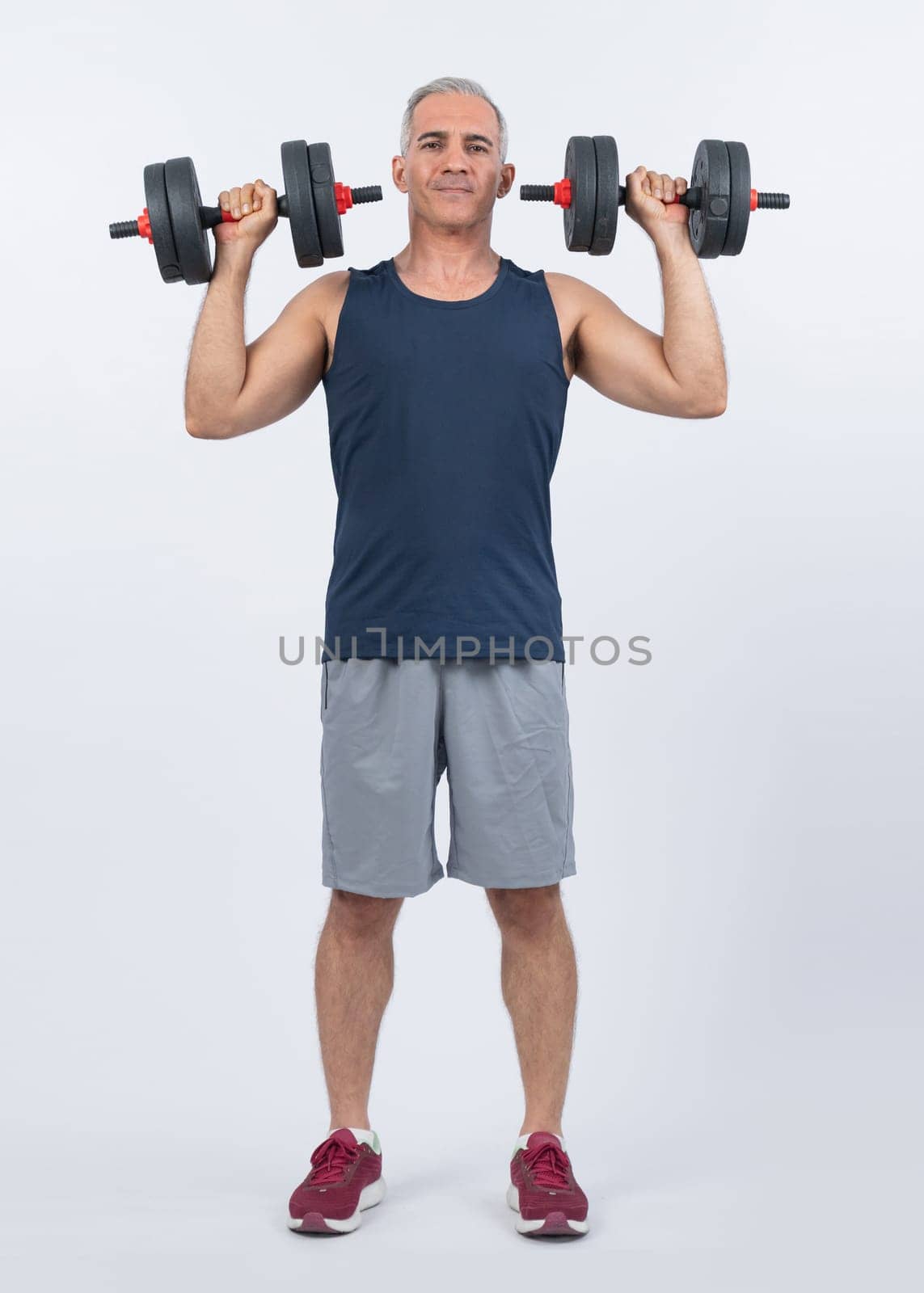 Full body length shot active and sporty senior man lifting dumbbell. Clout by biancoblue