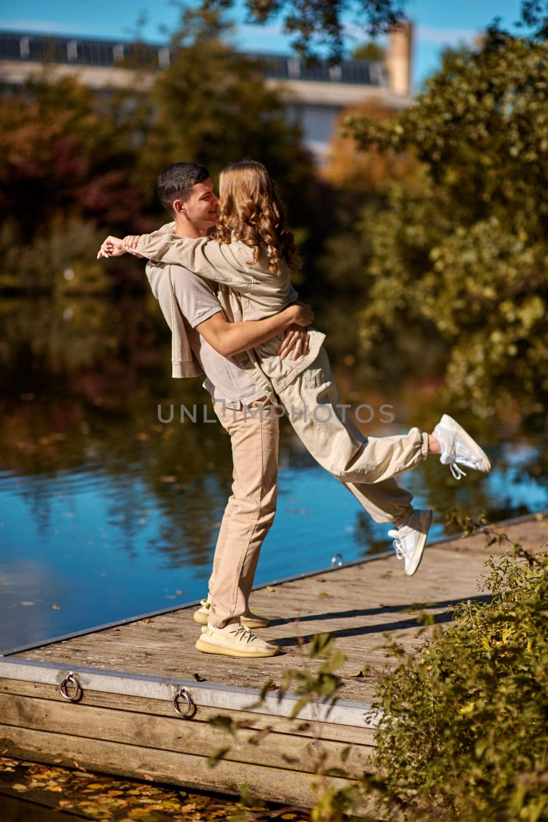 A happy couple in love in casual clothes travel together, hike and have fun in the fall forest on a weekend in nature in autumn outdoors, selective focus. Handsome man embracing with passion his girlfriend outdoor under the leaves of trees on the embankment. Love history. Happy people concept