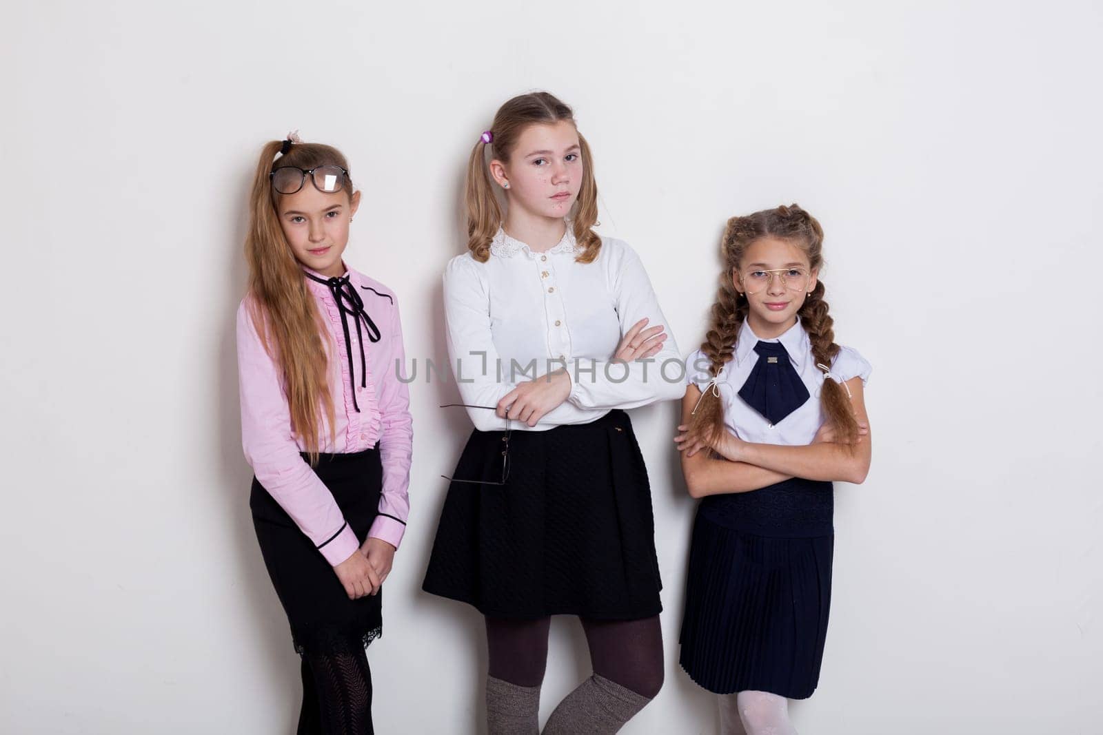 three schoolgirl girls in class at the white wall