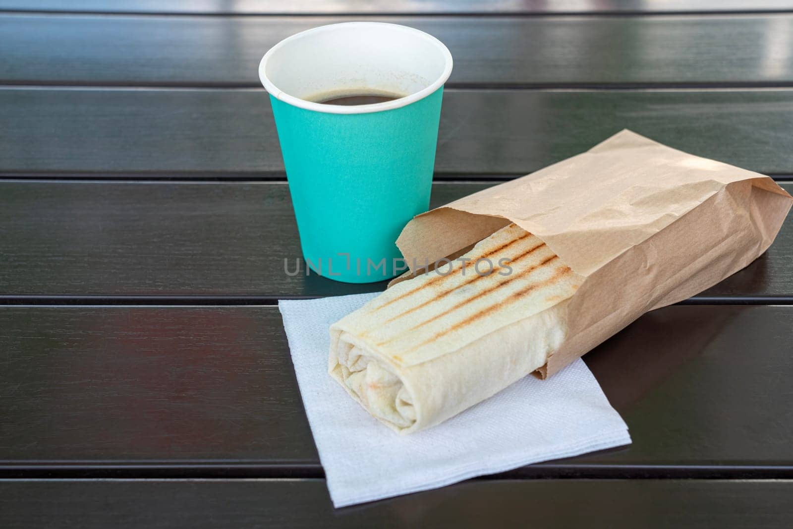 a glass of coffee and shawarma in lavash on the table. photo