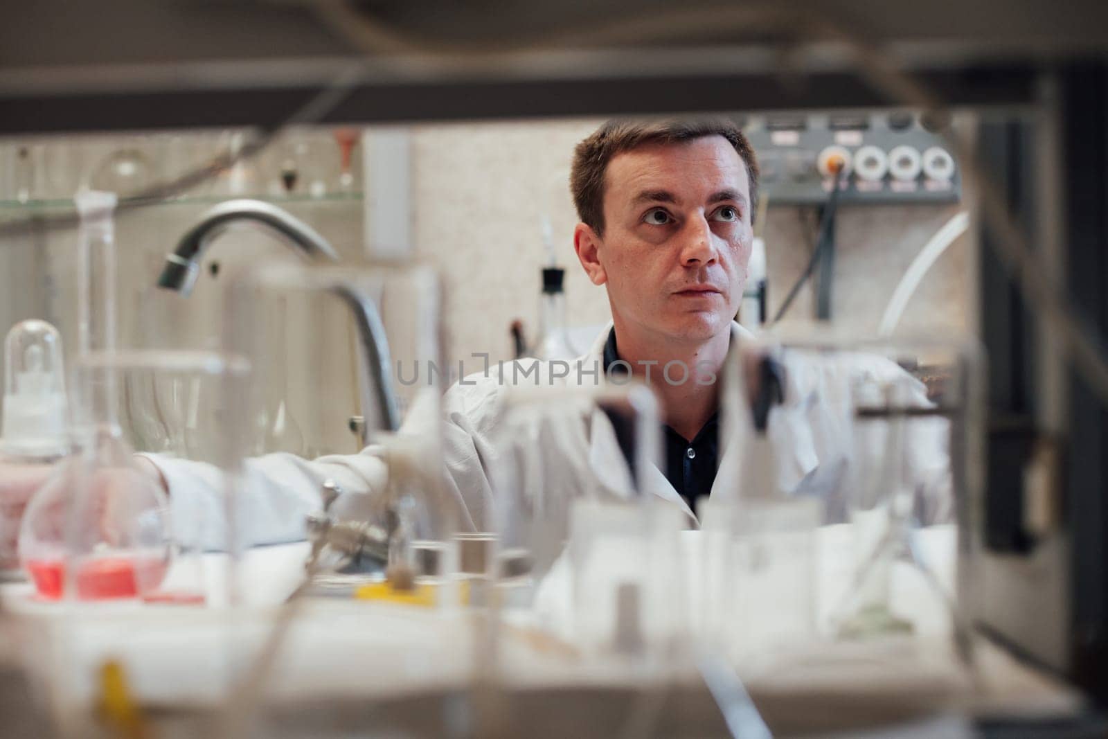 male scientist conducts chemical experiments in medical science laboratory by Simakov