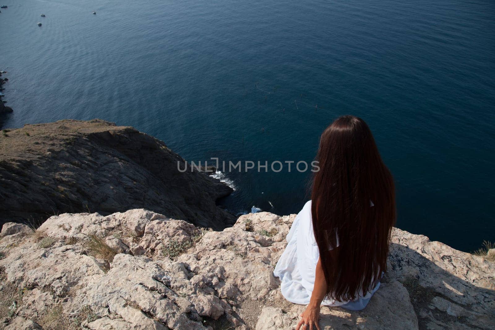 woman with long hair in dress on cliff cliff by the sea