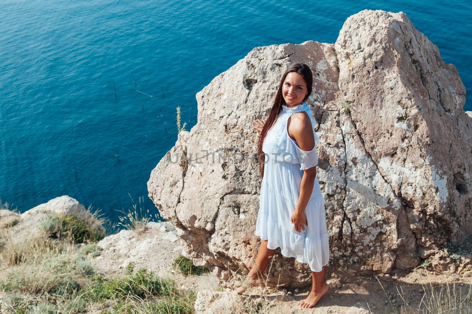 woman with long hair in dress on cliff cliff by the sea