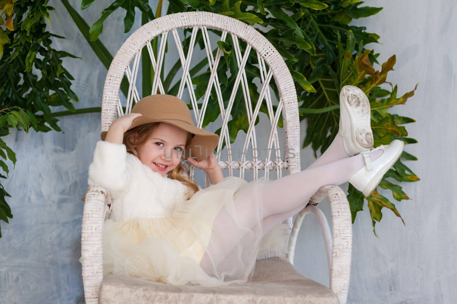 fashionable girl in a hat with fields sitting in a white chair