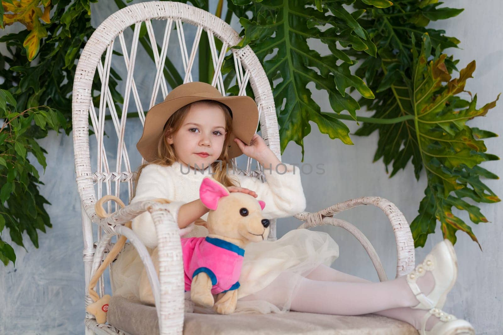 beautiful fashionable girl in a hat with fields sitting in a white chair by Simakov