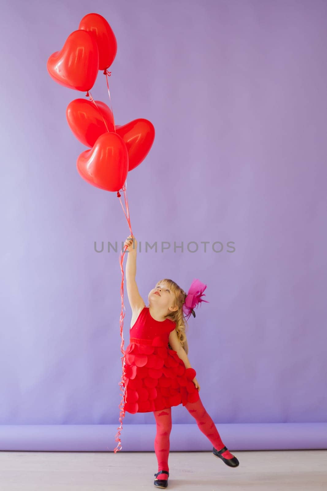 Girl with red heart-shaped balloons on birthday
