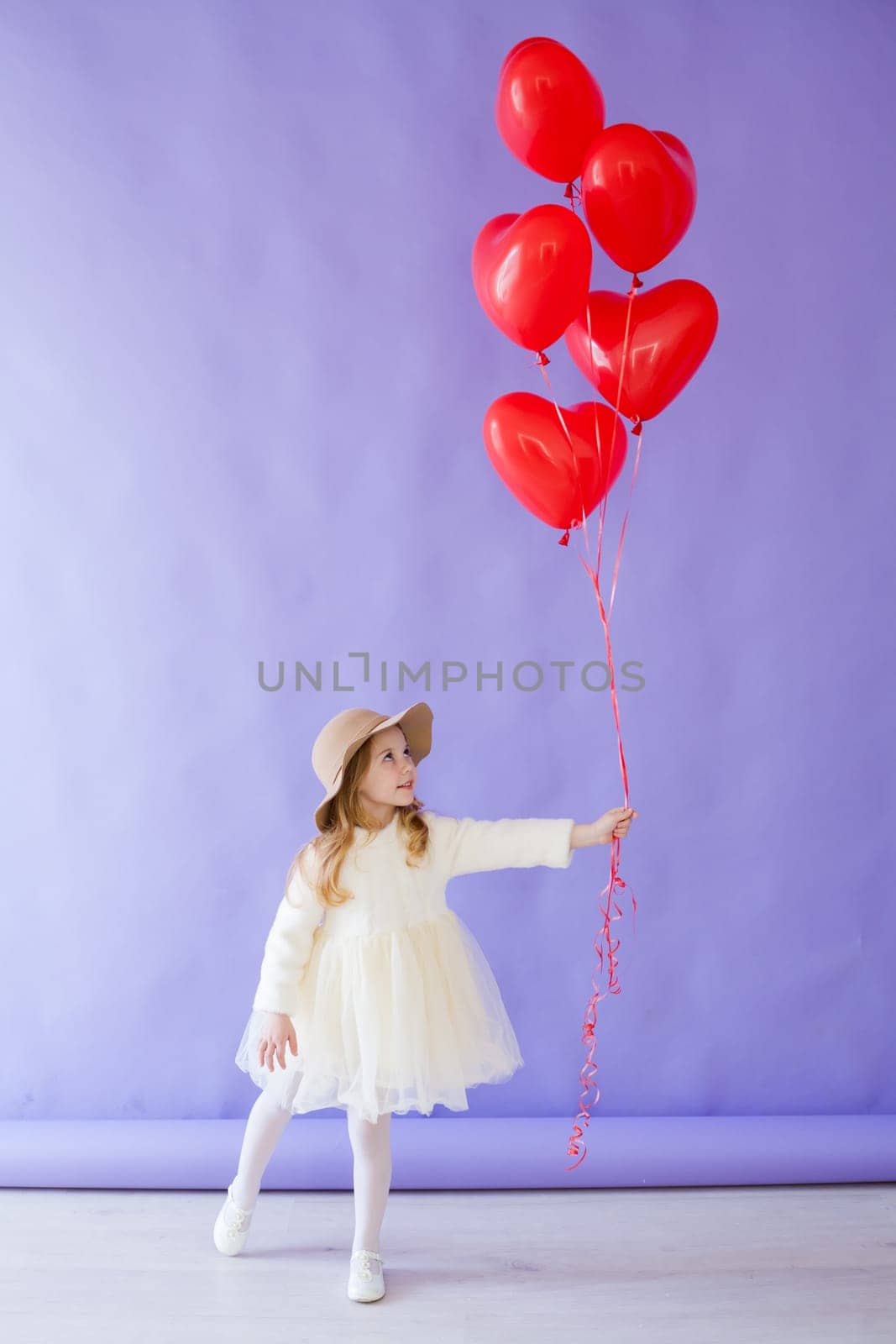 Girl with red heart-shaped balloons on birthday
