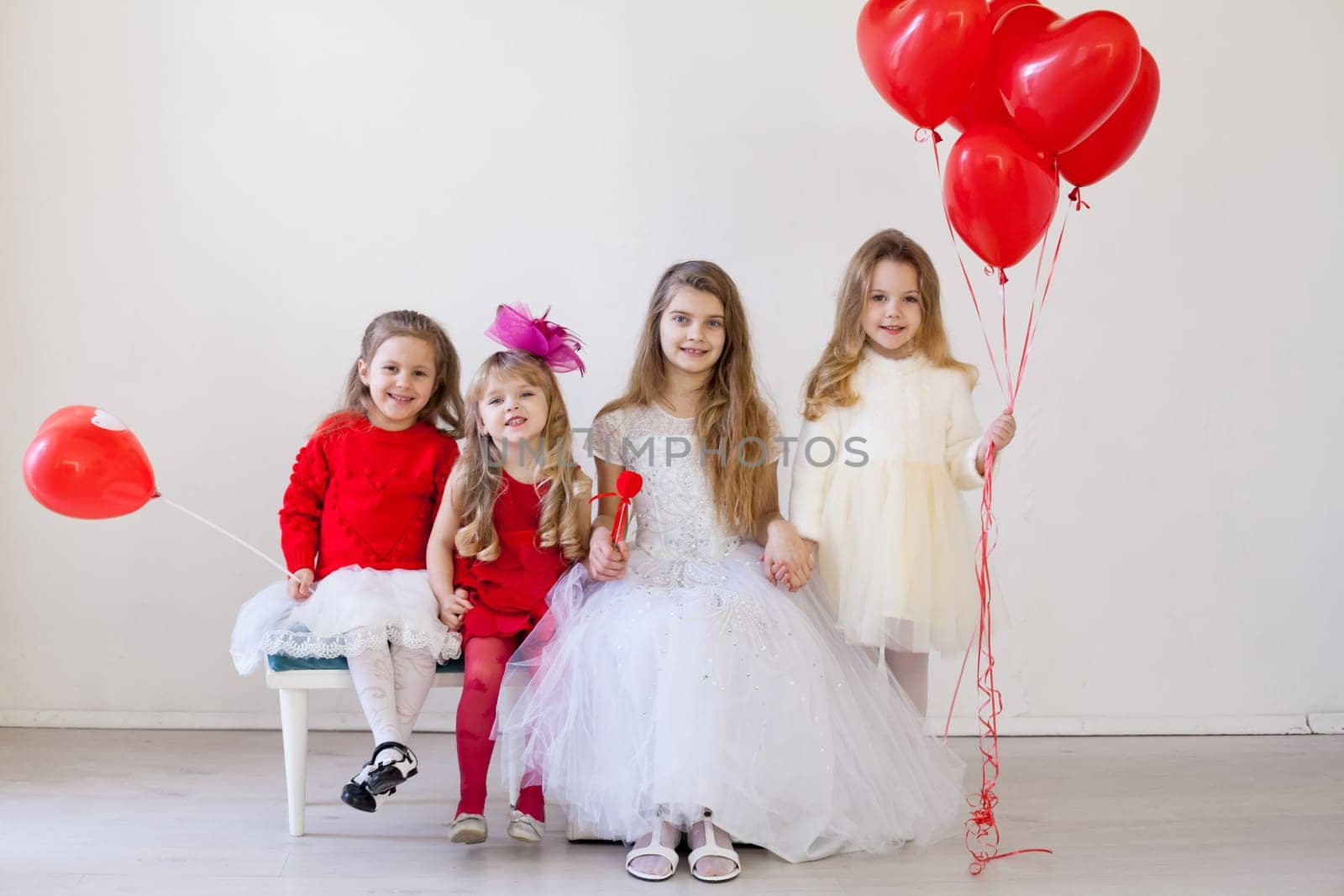 Girls with red heart-shaped balloons on birthday party by Simakov