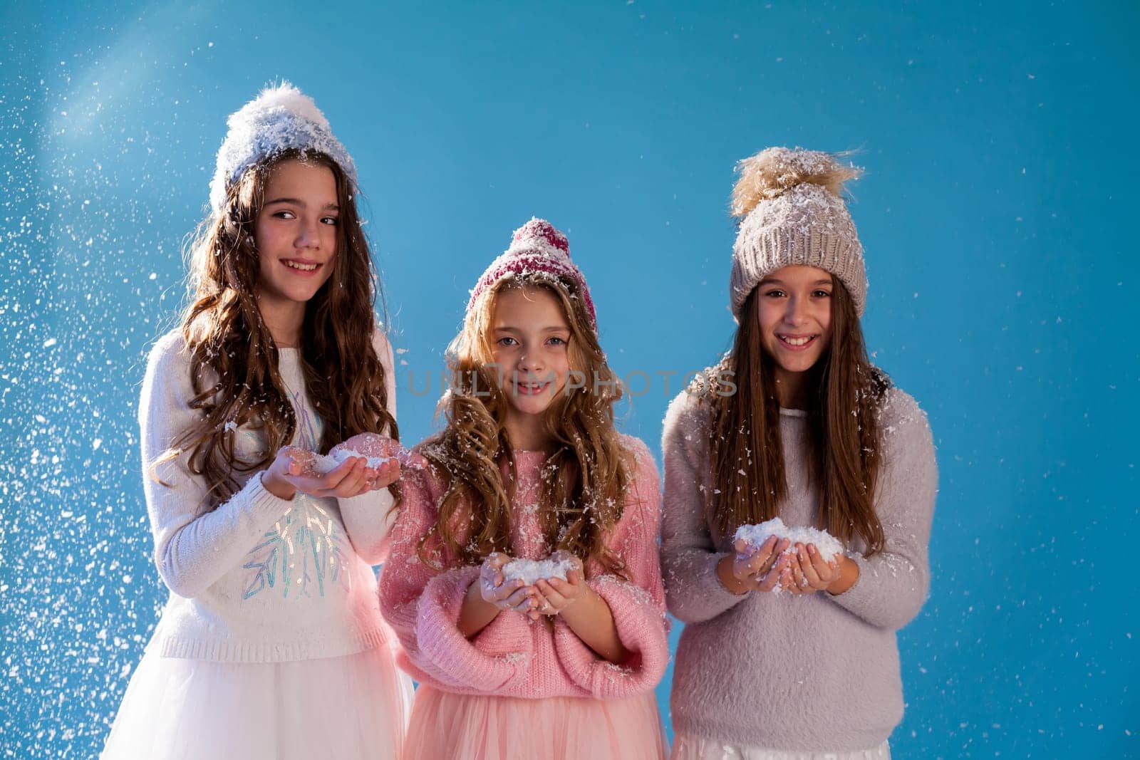 Three beautiful fashionable girls in winter snow caps by Simakov