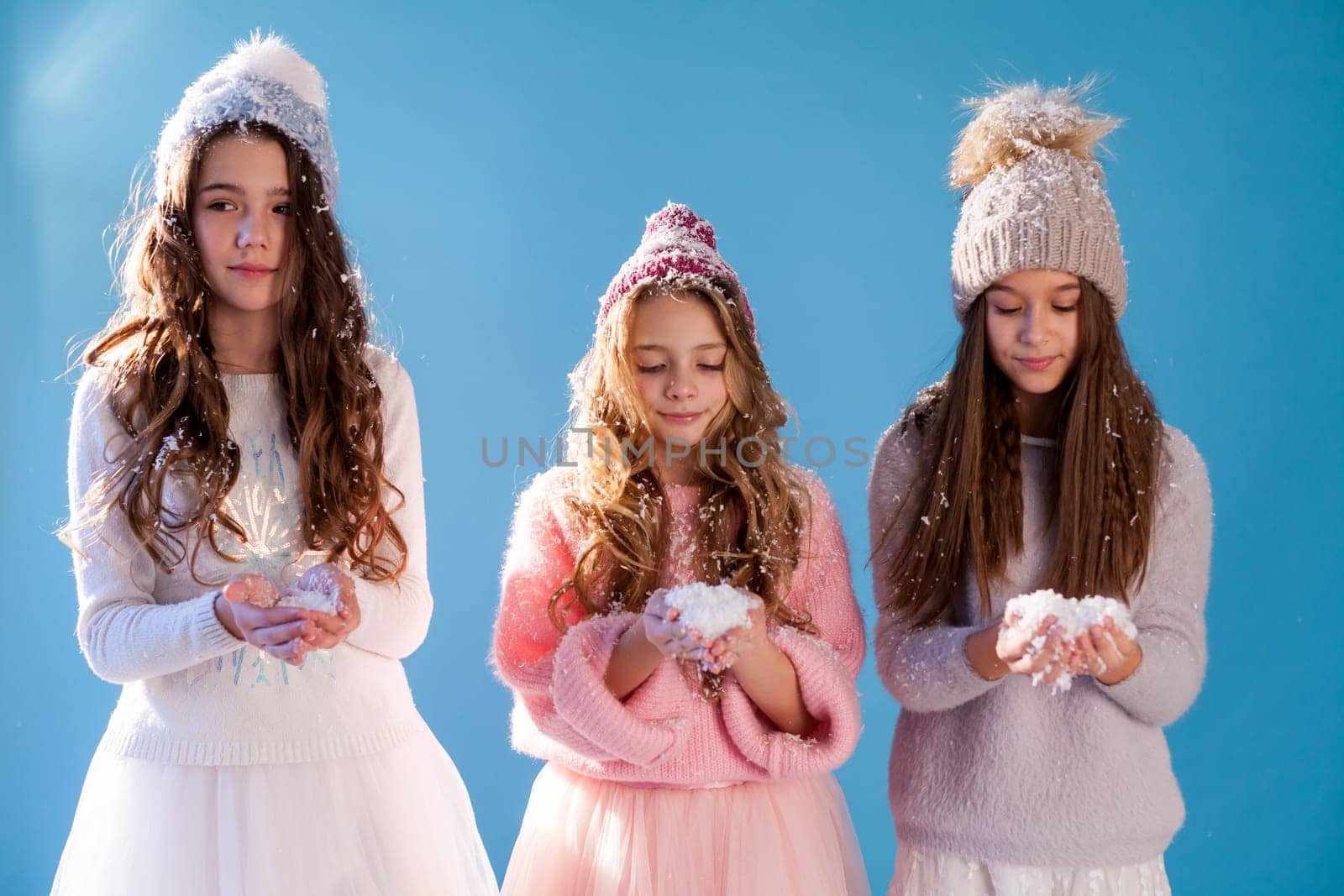 Three beautiful fashionable girls in winter snow caps by Simakov