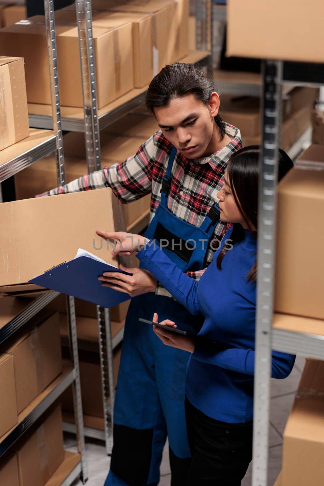 Warehouse managers taking parcel from shelf and checking code on digital tablet. Retail storehouse asian coworkers managing customer order picking, packing and shipping in storage room