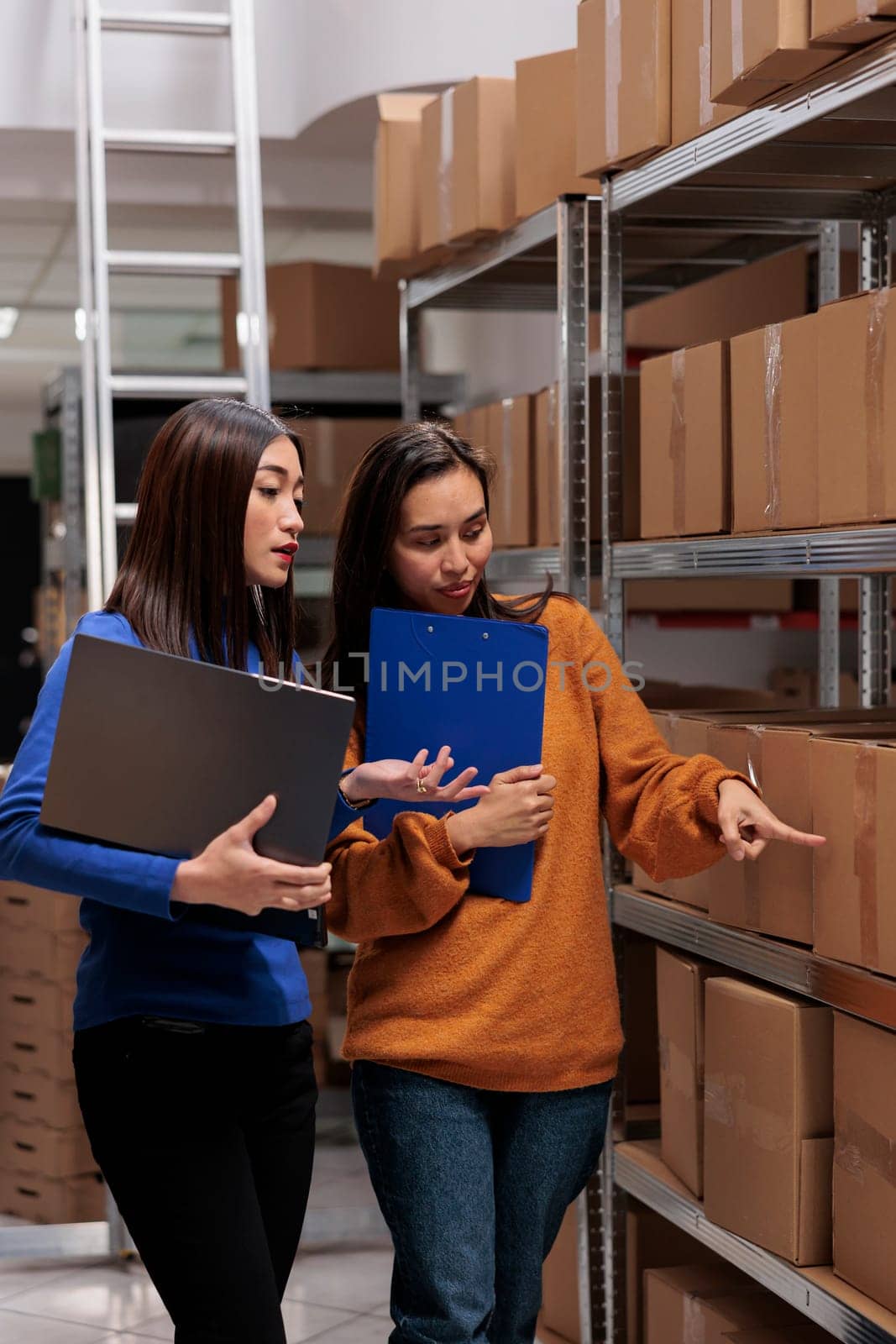 Warehouse managers checking goods maintenance in storage room. Storehouse asian women workers doing quality control operation and using inventory management software on laptop