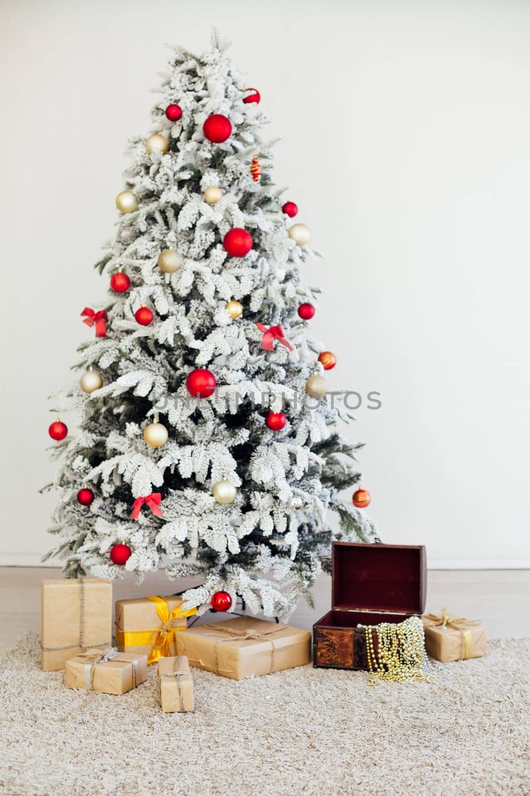 Green Christmas tree with Christmas gifts in white room