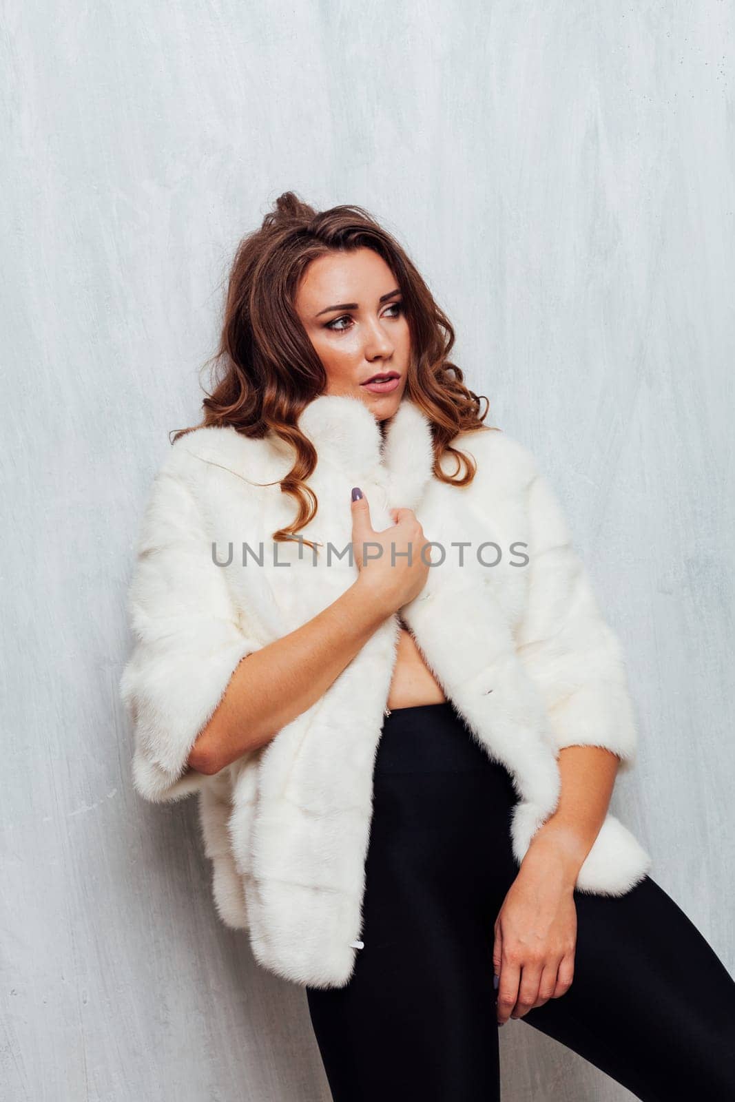 portrait of a beautiful woman with curls in a white fur coat and black skirt by Simakov