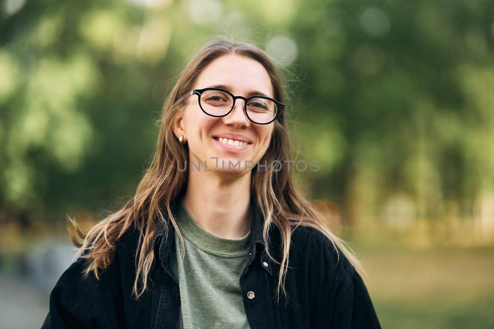 Portrait of a smiling young girl with glasses in the park. High-quality photo
