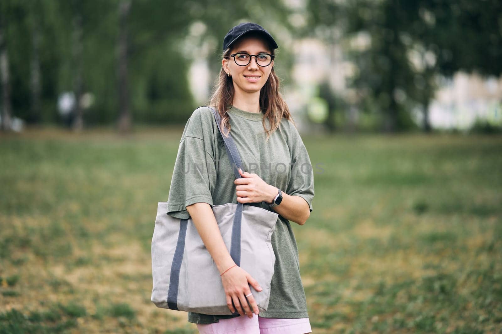 Young woman with glasses holding empty cotton eco bag, mockup design. by driver-s