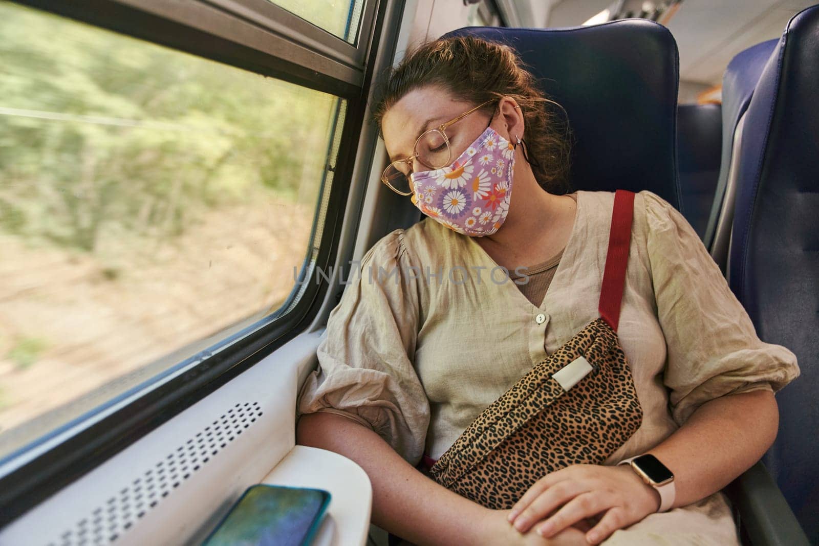 A girl with glasses in a medical mask sleeping on the train by driver-s