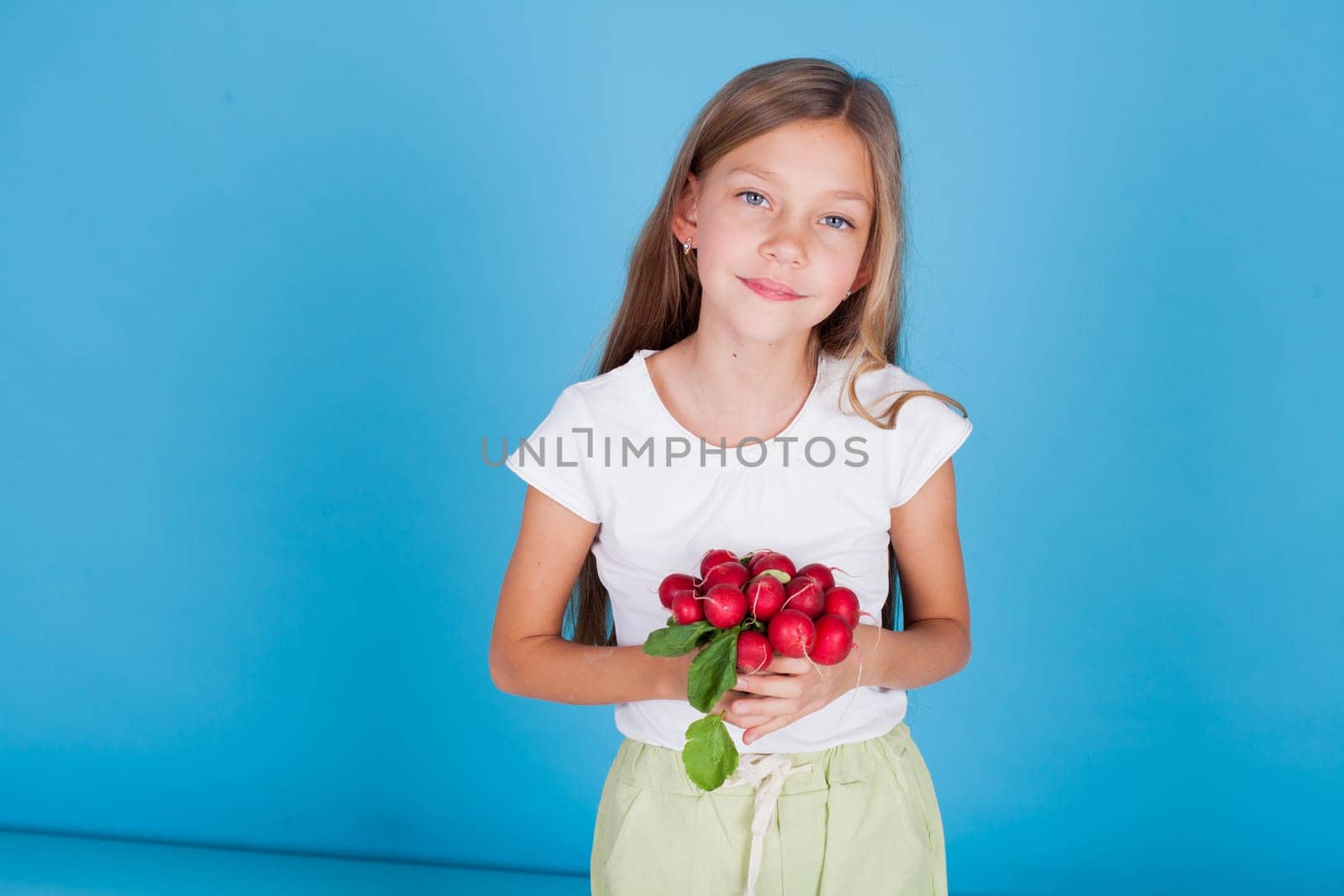 Beautiful little girl holds ripe vegetables for food by Simakov