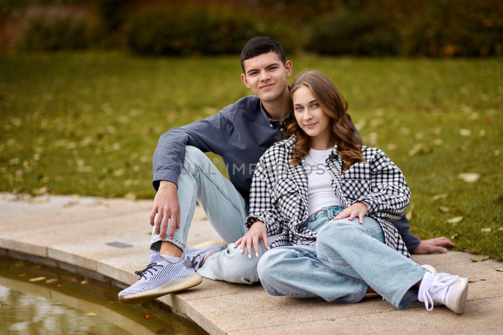 Young couple kissing and rejoices at the lake. lovely young couple kissing outdoors in autumn. Loving couple walking in nature. Autumn mood. Happy man and woman hugging and kissing in autumn. Love. Fashionable couple outdoors. Fashion, people and lifestyle. Stylish couple in autumn outfit. by Andrii_Ko