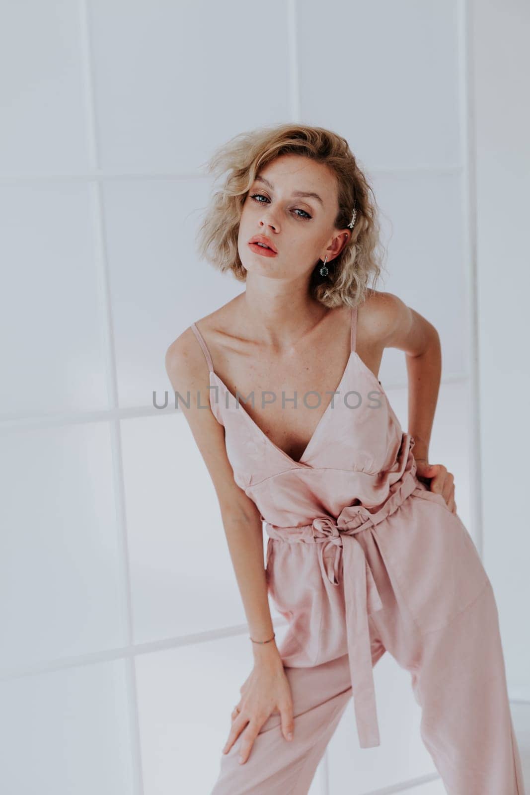 Portrait of a beautiful blonde woman in a pink jumpsuit