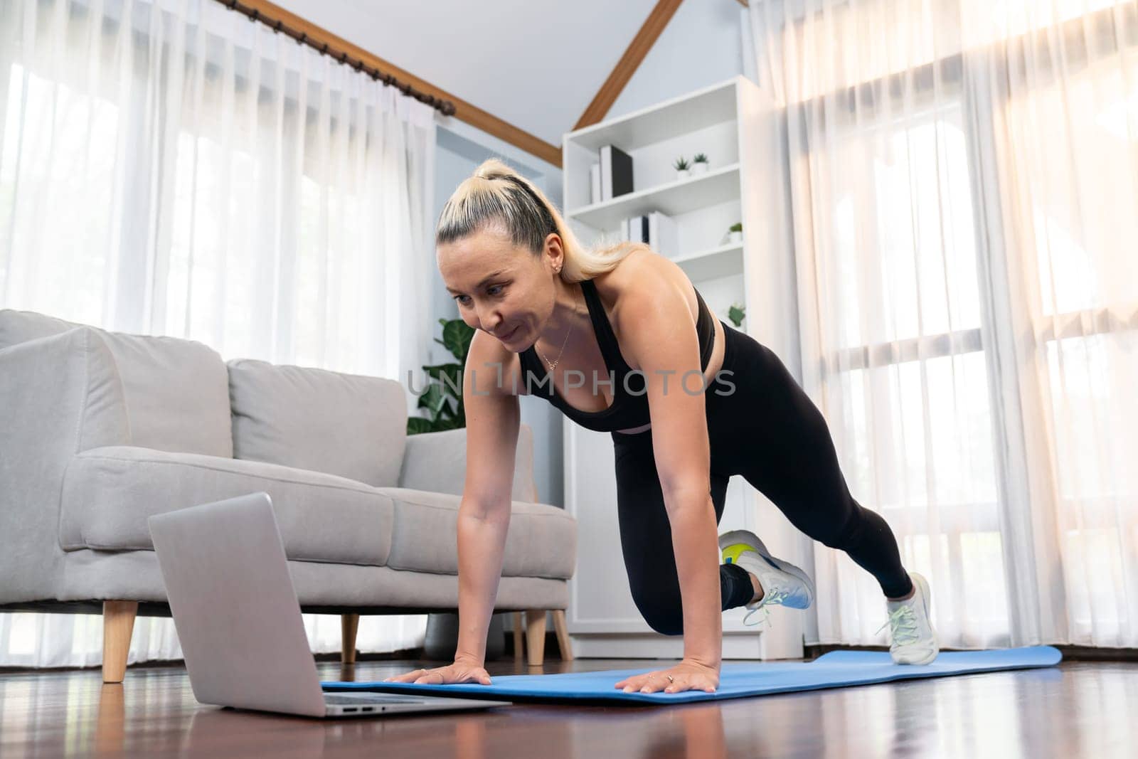 Athletic and active senior woman doing online plank climbing at home. Clout by biancoblue