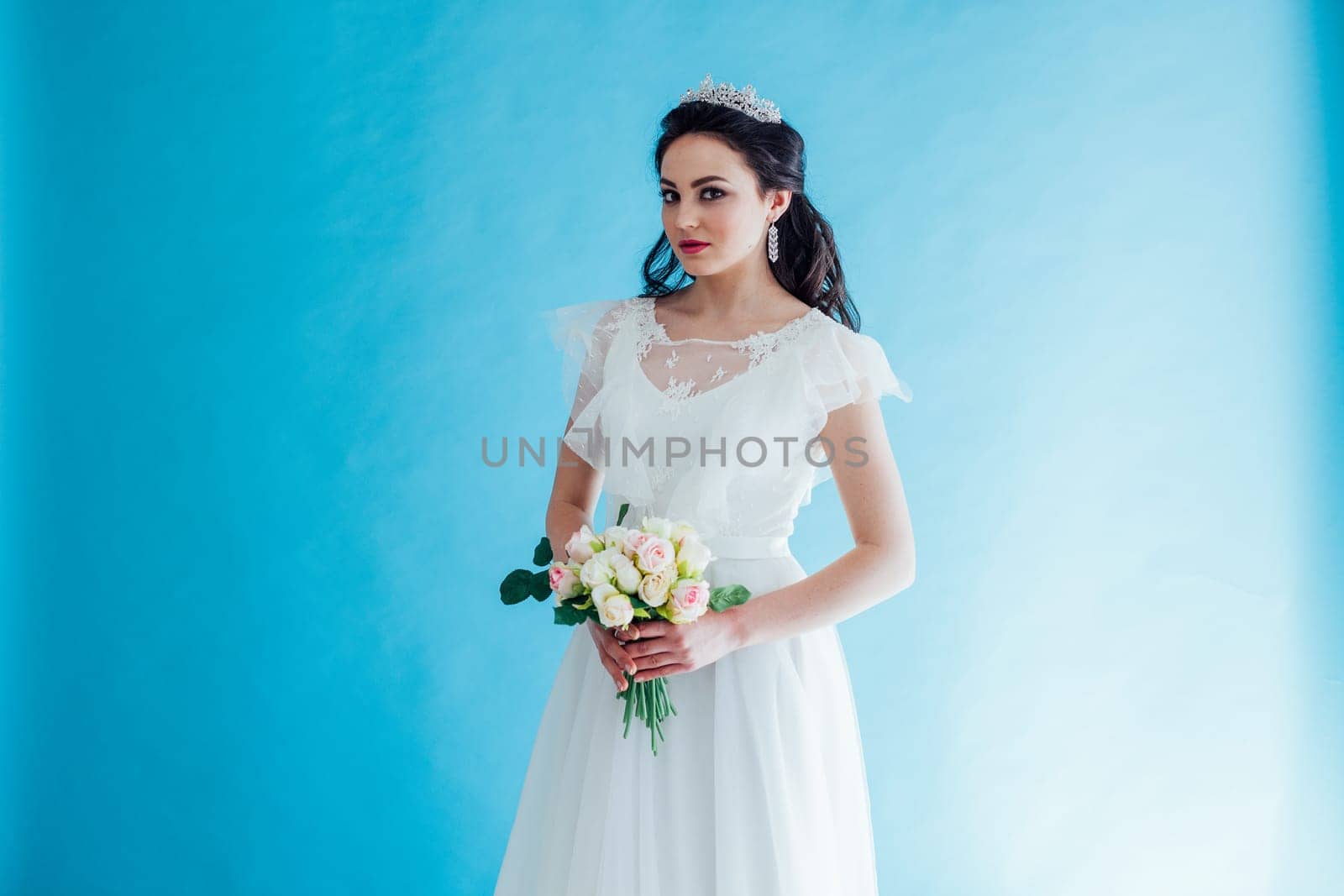 Princess Bride in a white dress with a Crown on a blue background flower in hands