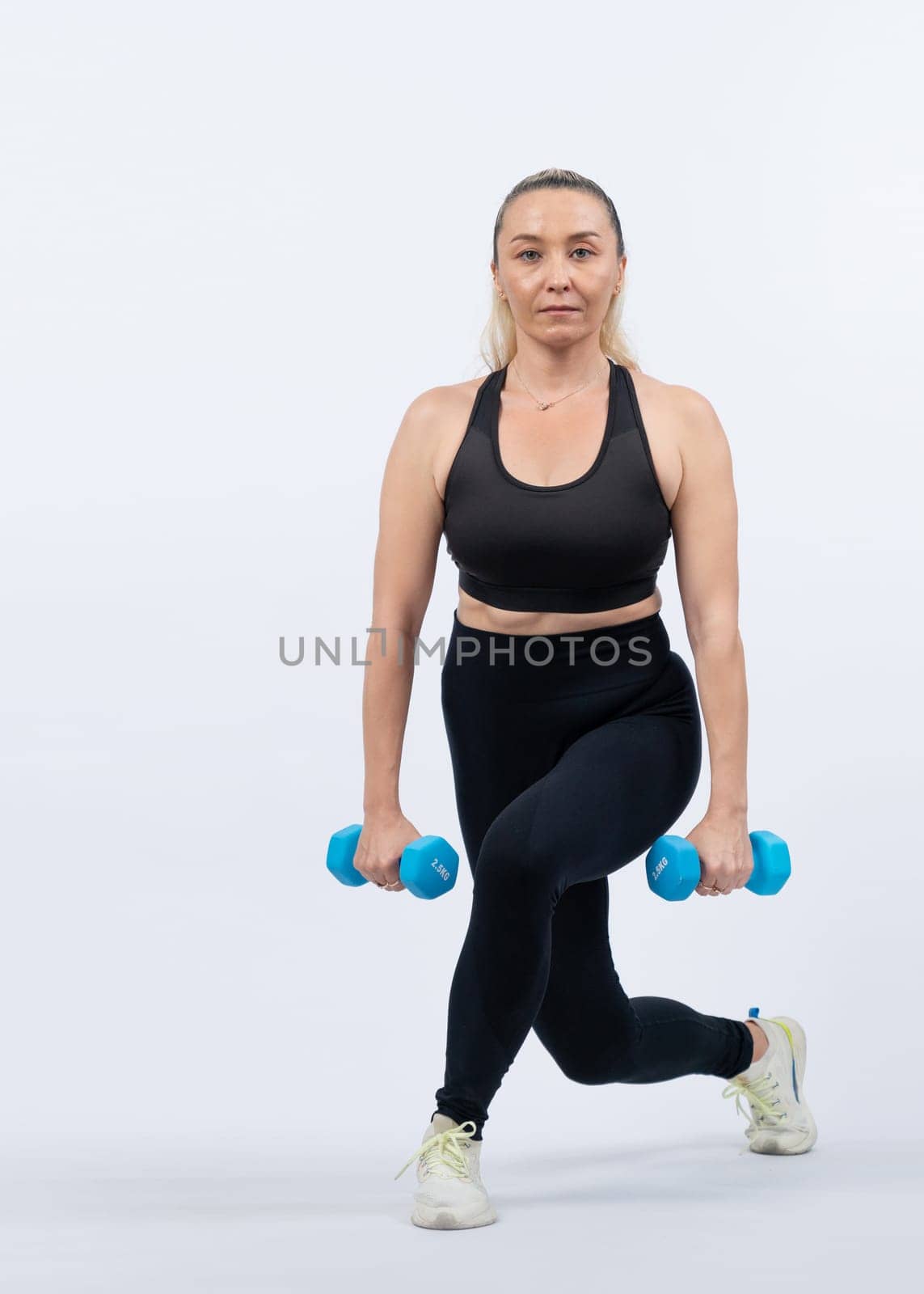 Full body length shot active and sporty senior woman lifting dumbbell. Clout by biancoblue