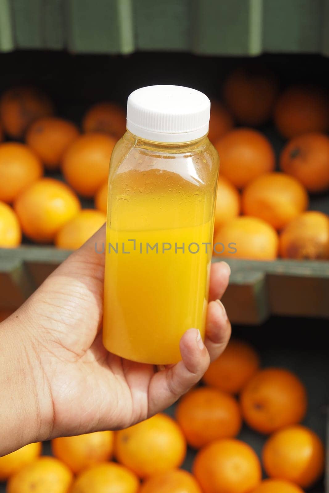 women holding a bottle of orange juice against against fruit background .