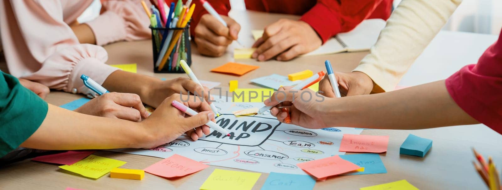 Creative business team brainstorming about marketing strategy and business plan by using mind mapping. Startup team work together to write down on paper. Focus on hand. Closeup. Variegated.