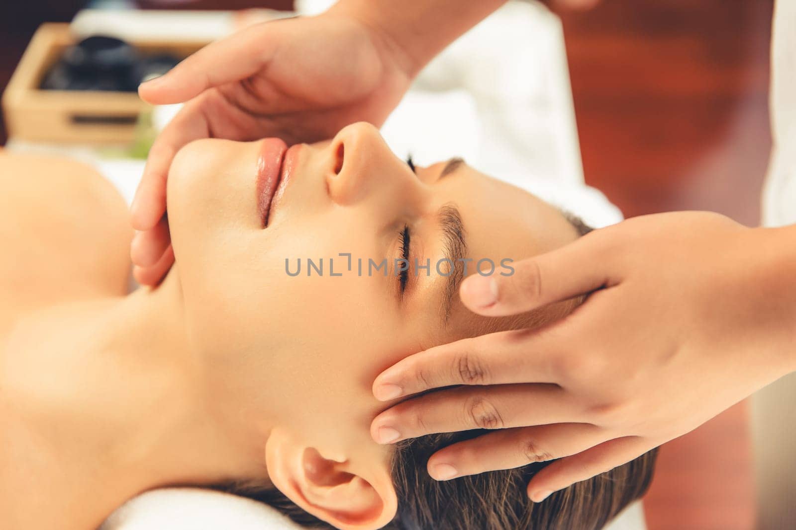 Closeup woman enjoying relaxing anti-stress head massage and pampering facial beauty skin recreation leisure in dayspa modern light ambient at luxury resort or hotel spa salon. Quiescent