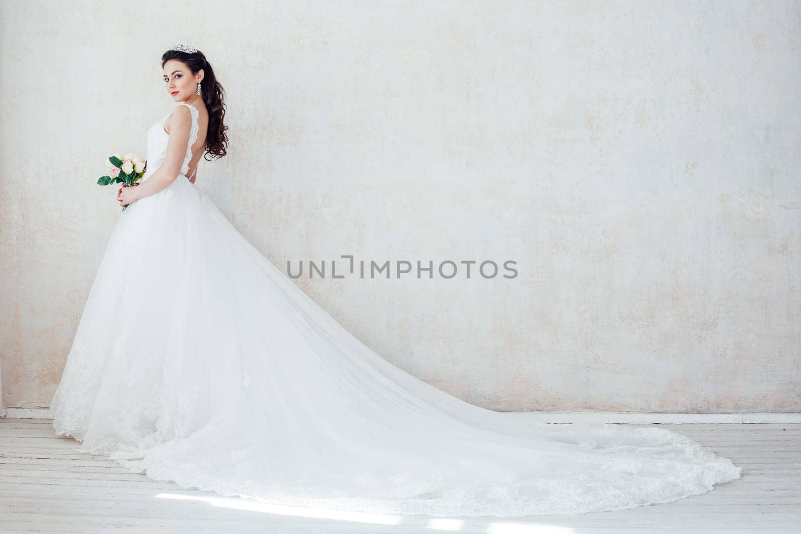 Princess Bride in a wedding dress with a train standing in a room of vintage