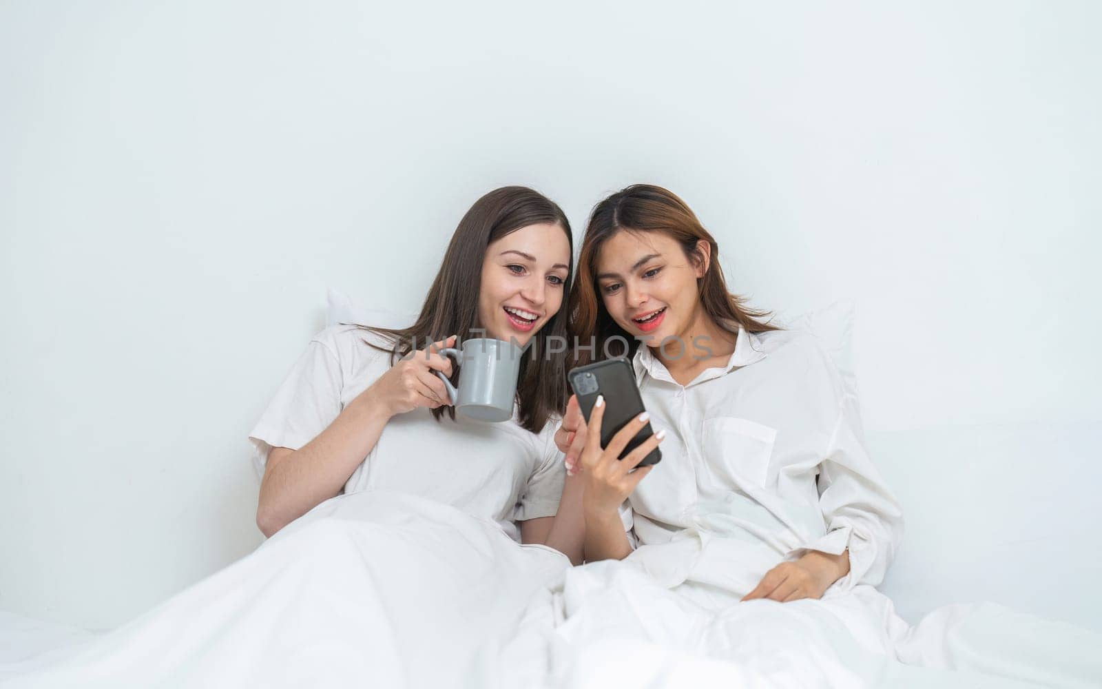 Young Asian lesbian couple sitting on bed during happy resting time Talk and relax in the bedroom..