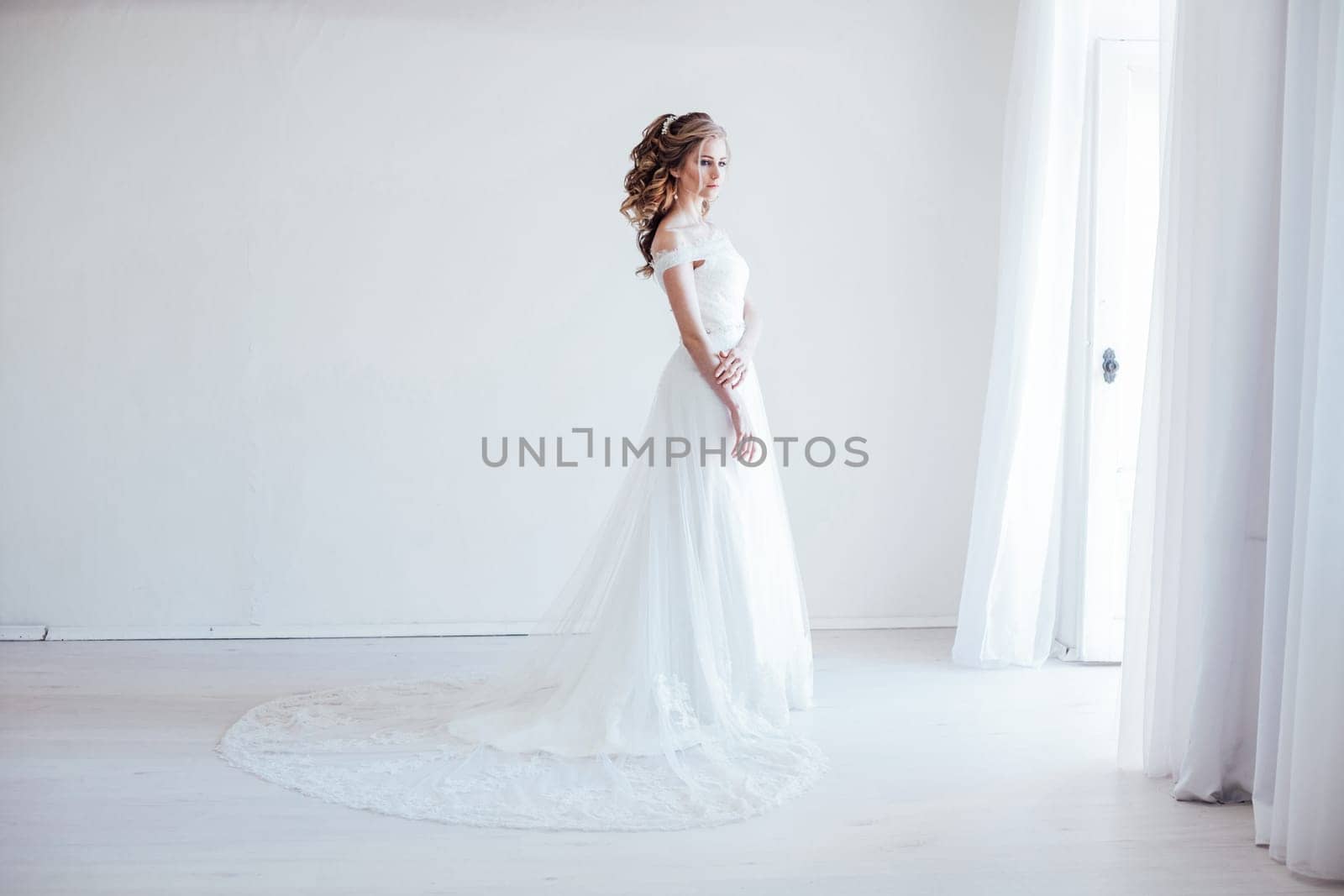 bride in wedding dress in a white room before wedding