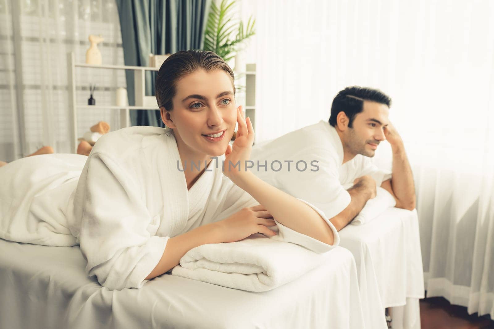 Caucasian couple customer enjoying relaxing anti-stress spa massage and pampering with beauty skin recreation leisure in day light ambient salon spa at luxury resort or hotel. Quiescent