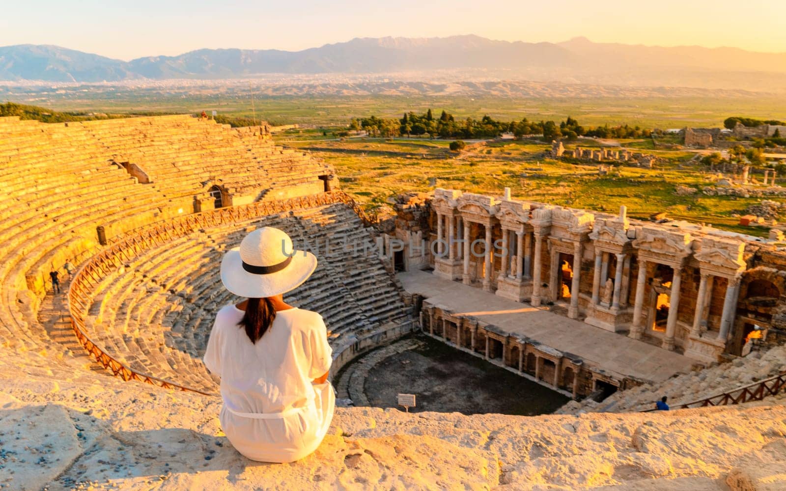 Hierapolis ancient city Pamukkale Turkey, young woman with hat watching sunset by the ruins Unesco by fokkebok