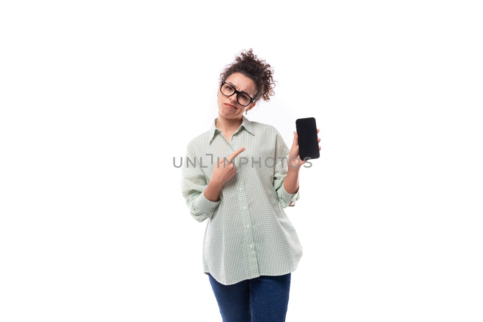 young leader woman with curly black hair in glasses dressed in a shirt holding a smartphone.