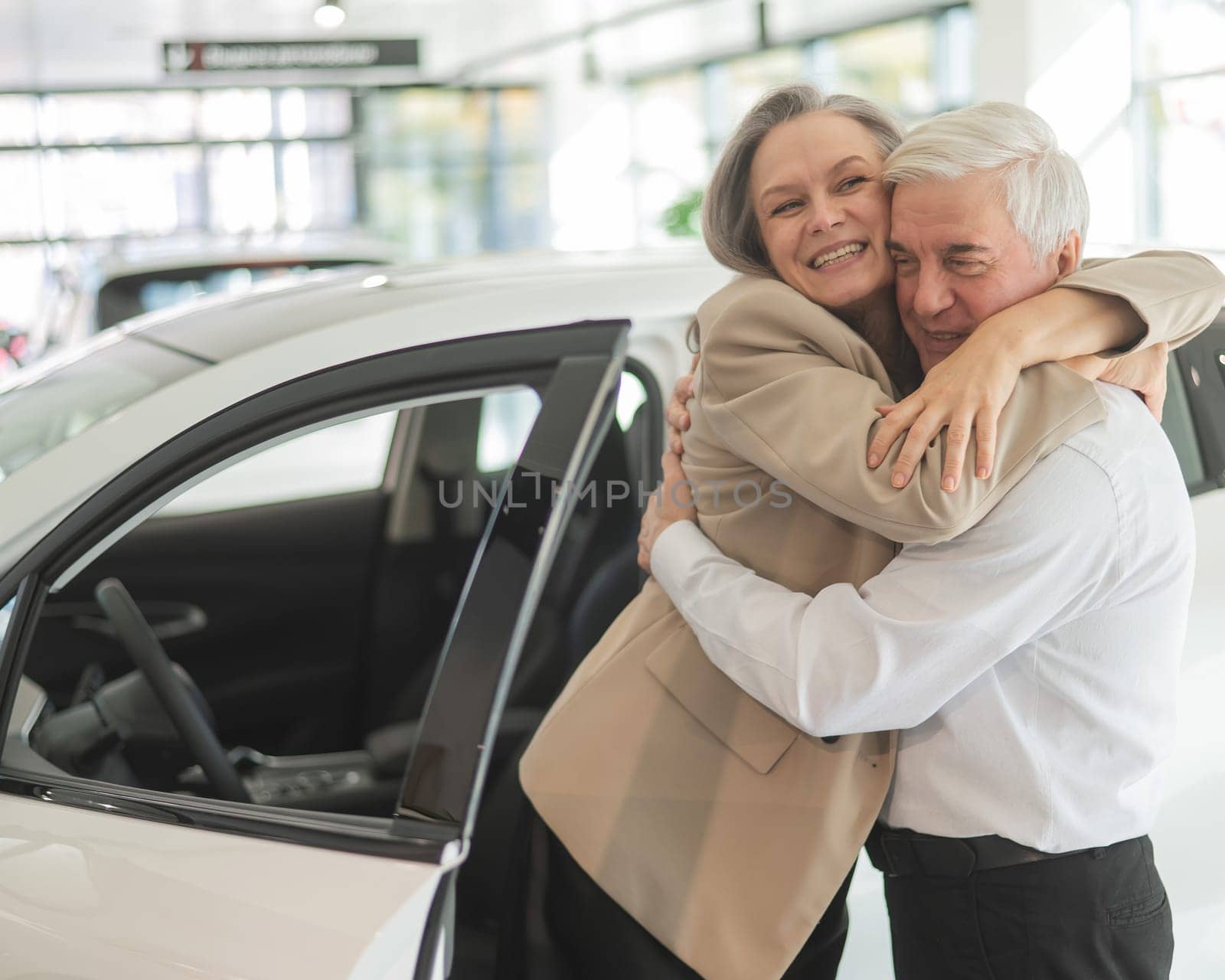 Mature Caucasian couple hugging. Elderly man and woman buying a new car. by mrwed54