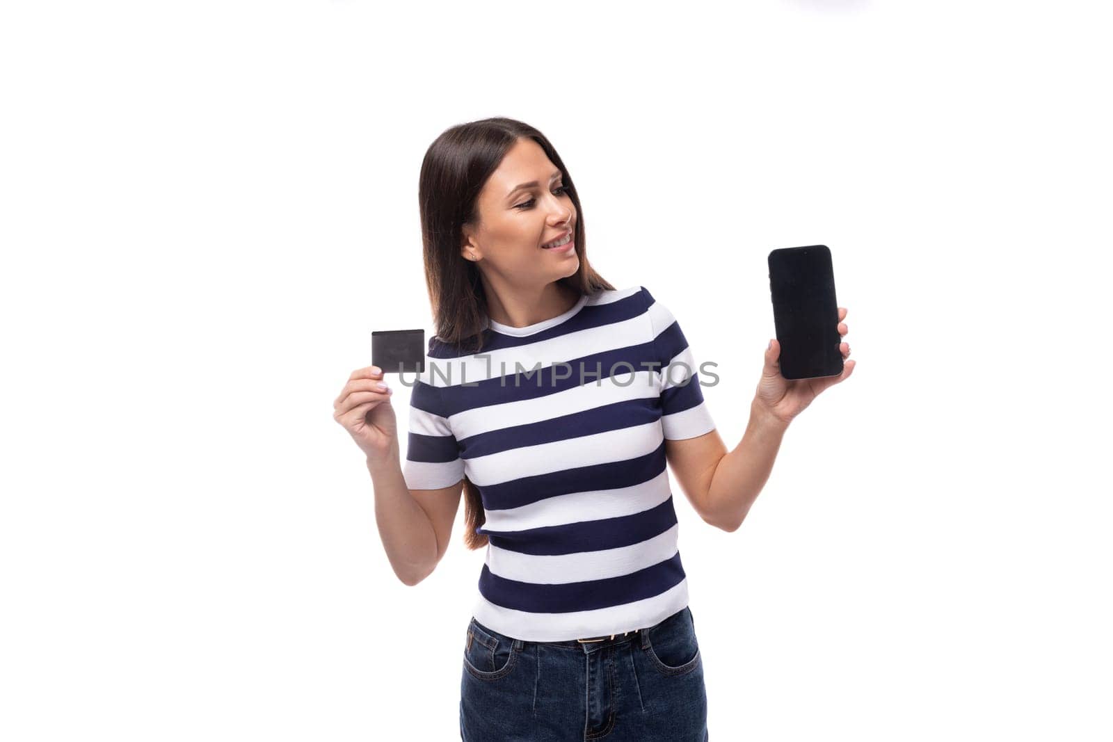 young smart brunette european lady of slim build dressed in black and white t-shirt offers advertising on smartphone holding credit card mockup by TRMK