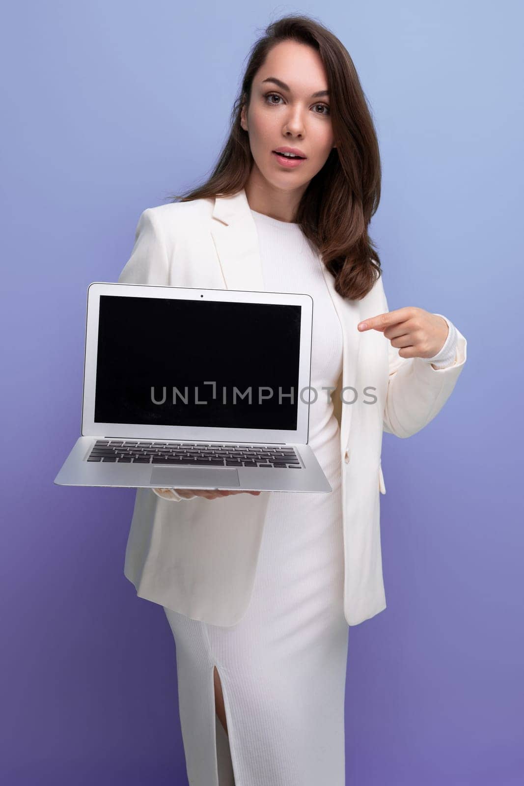 smiling brunette business women in white dress holding laptop for freelancing work.