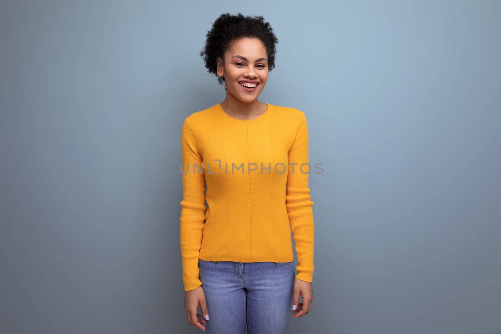 pretty 20s latin woman with afro hair in casual yellow blouse posing on studio background.