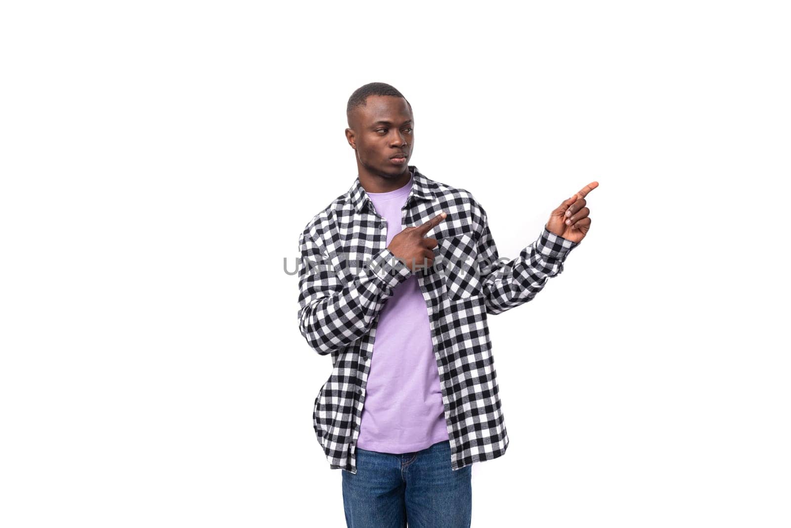 young smart african man dressed in a plaid shirt points a finger towards an advertisement on an isolated white background with copy space.