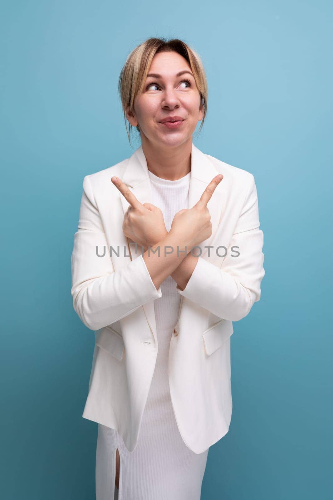 well-groomed young Caucasian blond lady in a white jacket and dress shows her fingers to the sides.