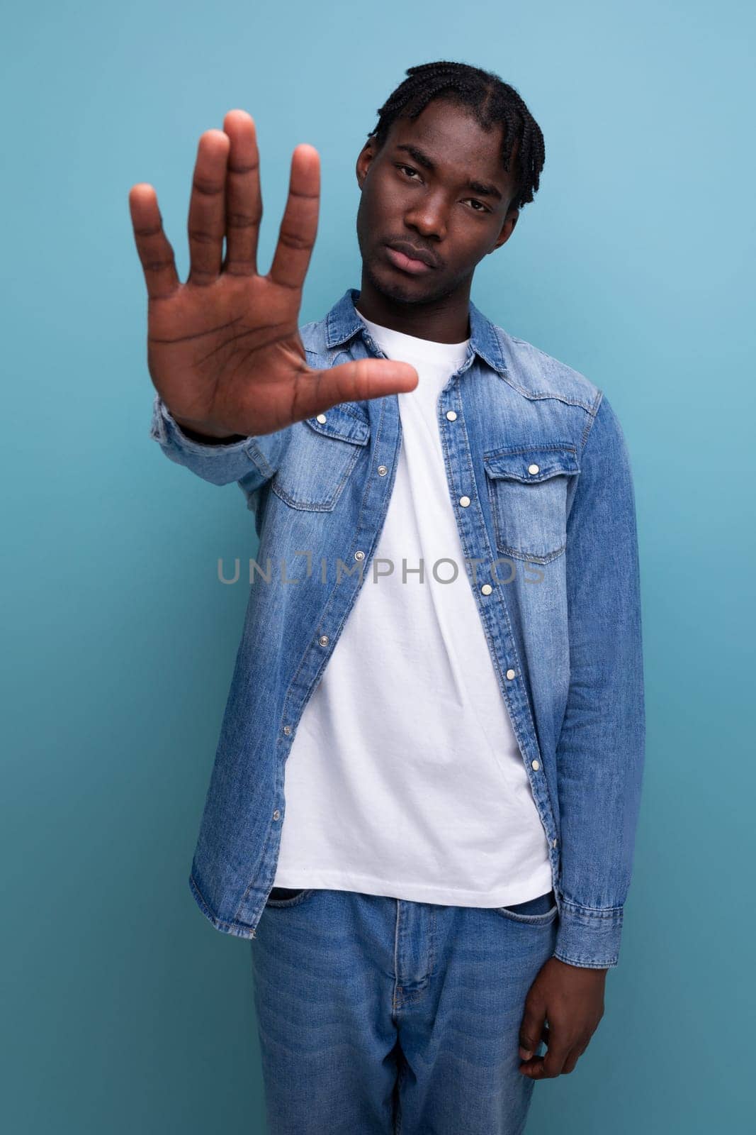 african man with dreadlocks shows stop gesture.