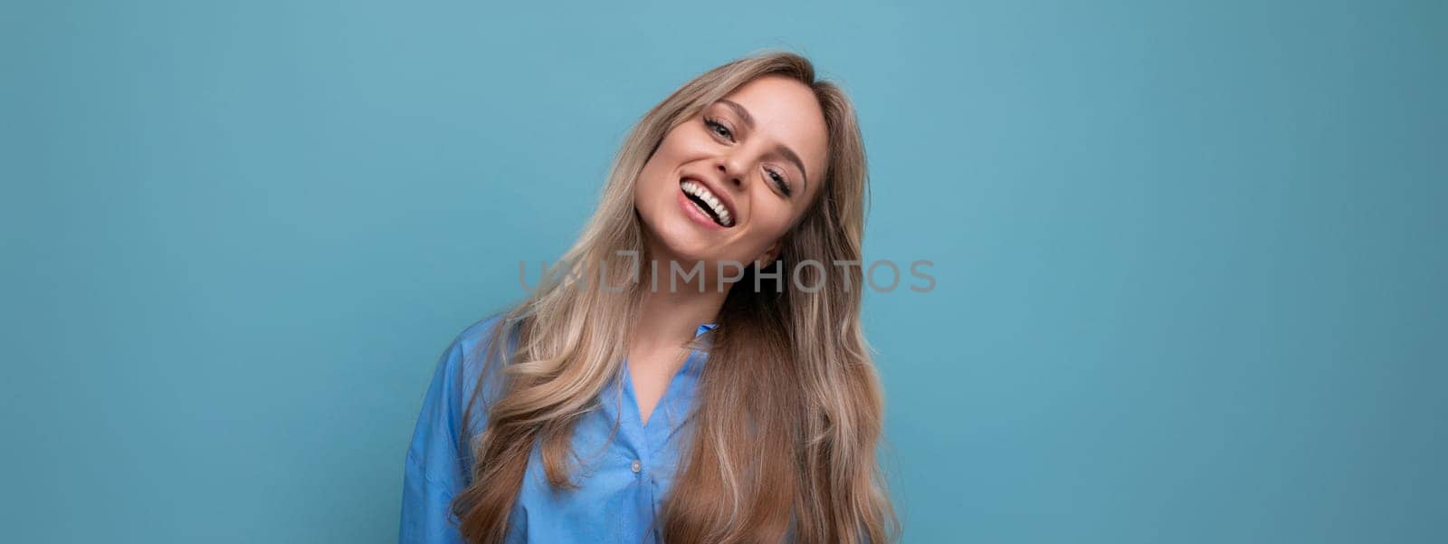 horizontal wide photo of adorable blonde young woman on blue background with empty space by TRMK