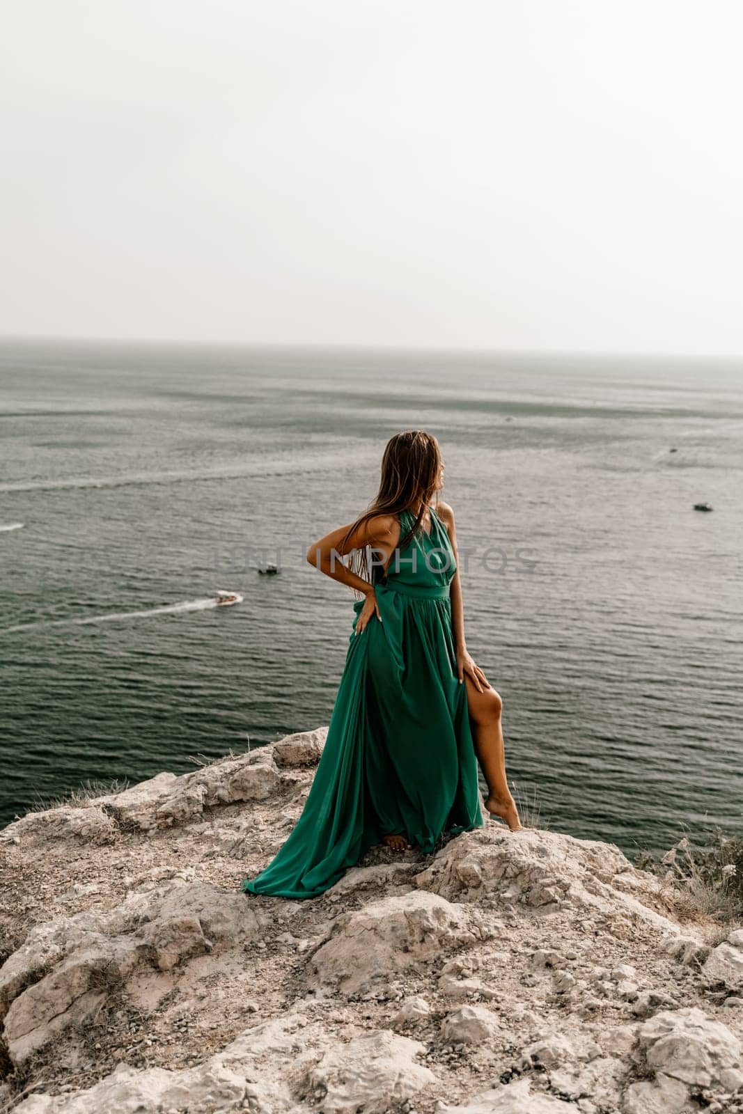 Woman sea trevel green dress. Side view a happy woman with long hair in a long mint dress posing on a beach with calm sea bokeh lights on sunny day. Girl on the nature on blue sky background