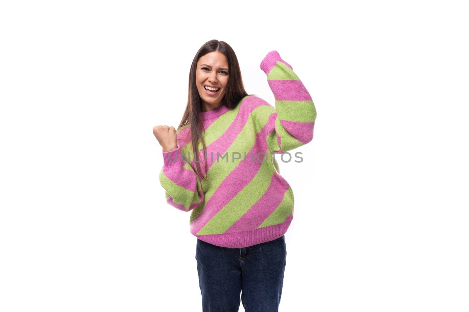 pretty positive cheerful young european brunette woman dressed in a striped pink-green pullover on a white background with copy space.