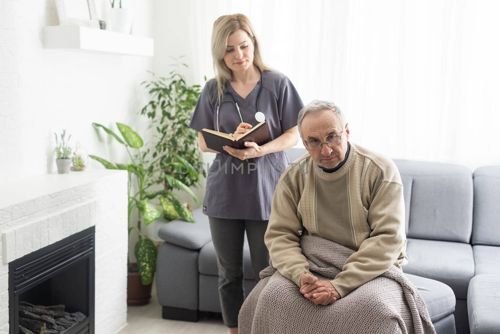 Caring nurse talks to old patient holds his hand sit in living room at homecare visit provide psychological support listen complains showing empathy encouraging. Geriatrics medicine caregiving concept by Andelov13