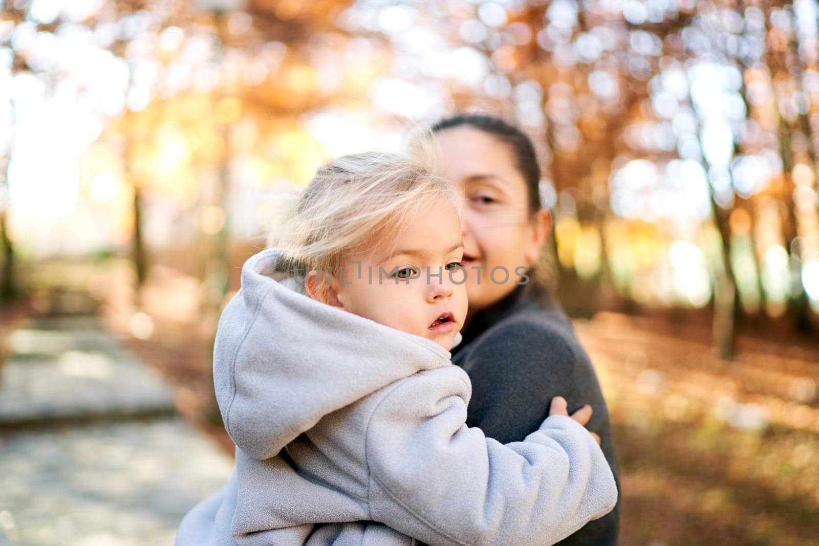 Little girl sits in her mother arms and looks away. High quality photo